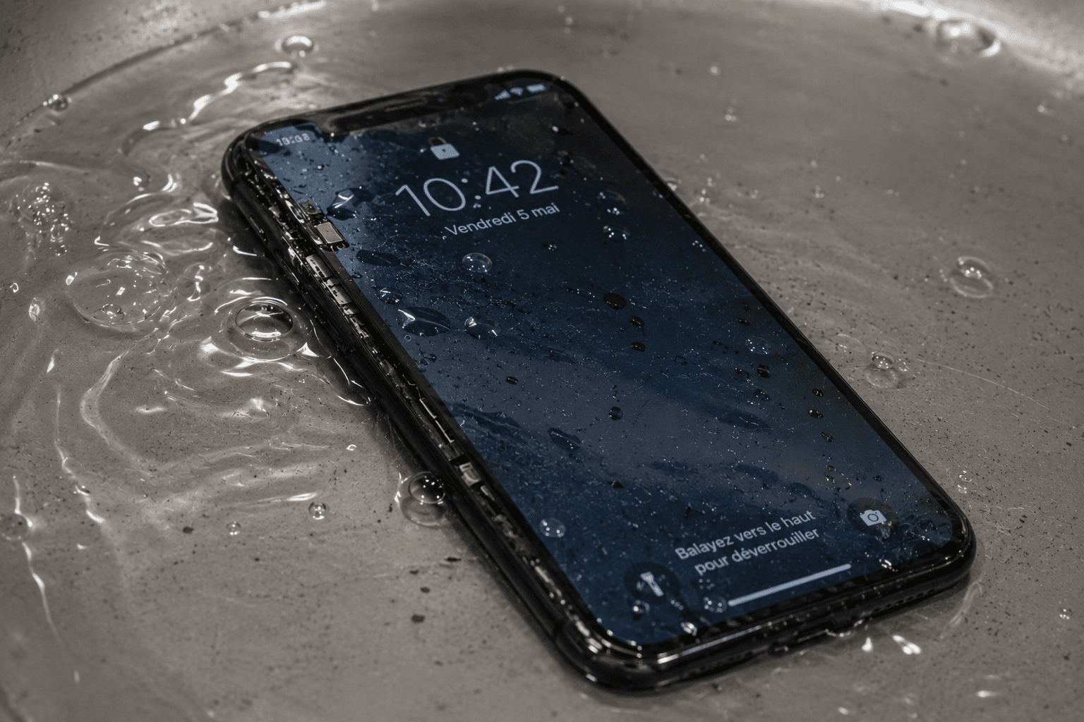 iPhone tombé dans l'eau avec des gouttes sur l'écran