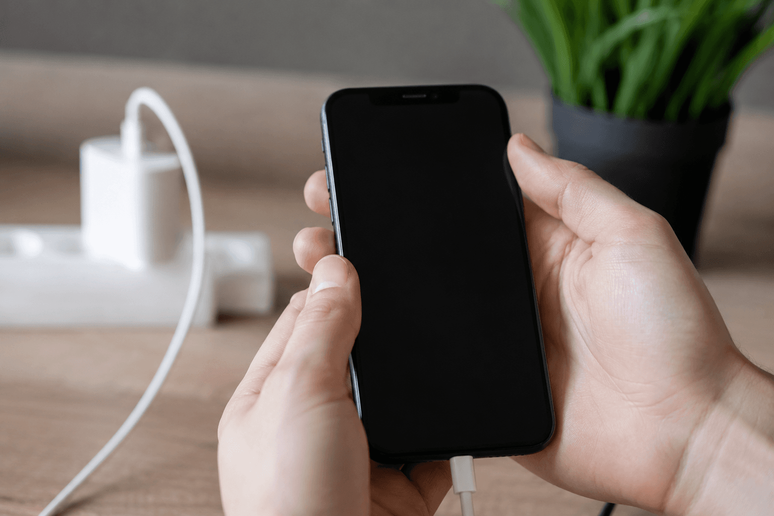 iPhone avec écran noir branché sur un chargeur