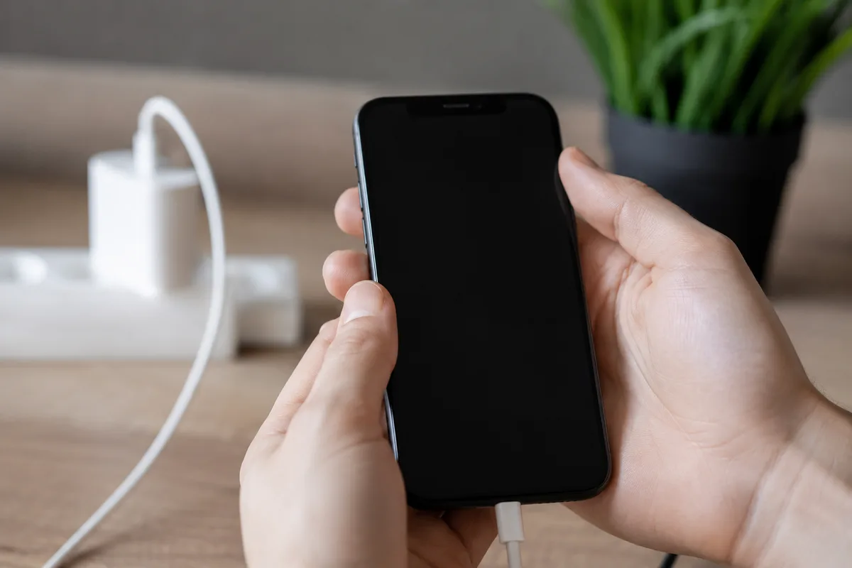 iPhone avec écran noir branché sur un chargeur